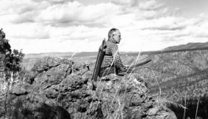 black and white photo of aldo leopold sitting on a rock cliff